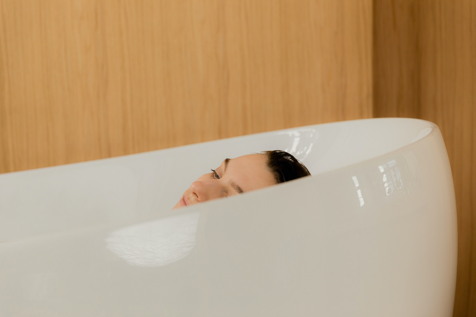 relaxed woman in white bathtub with bamboo wall